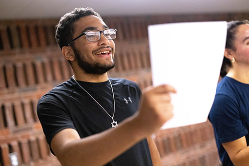 Tyler J. reads a sheet of paper in a classroom.