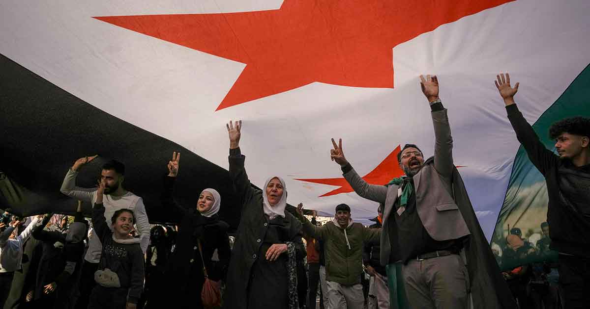 Syrians celebrate underneath a revoutionary flag in Damascus.