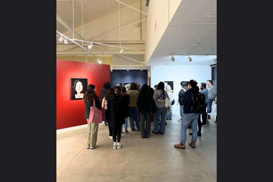 A group of people in an art gallery walking into another room