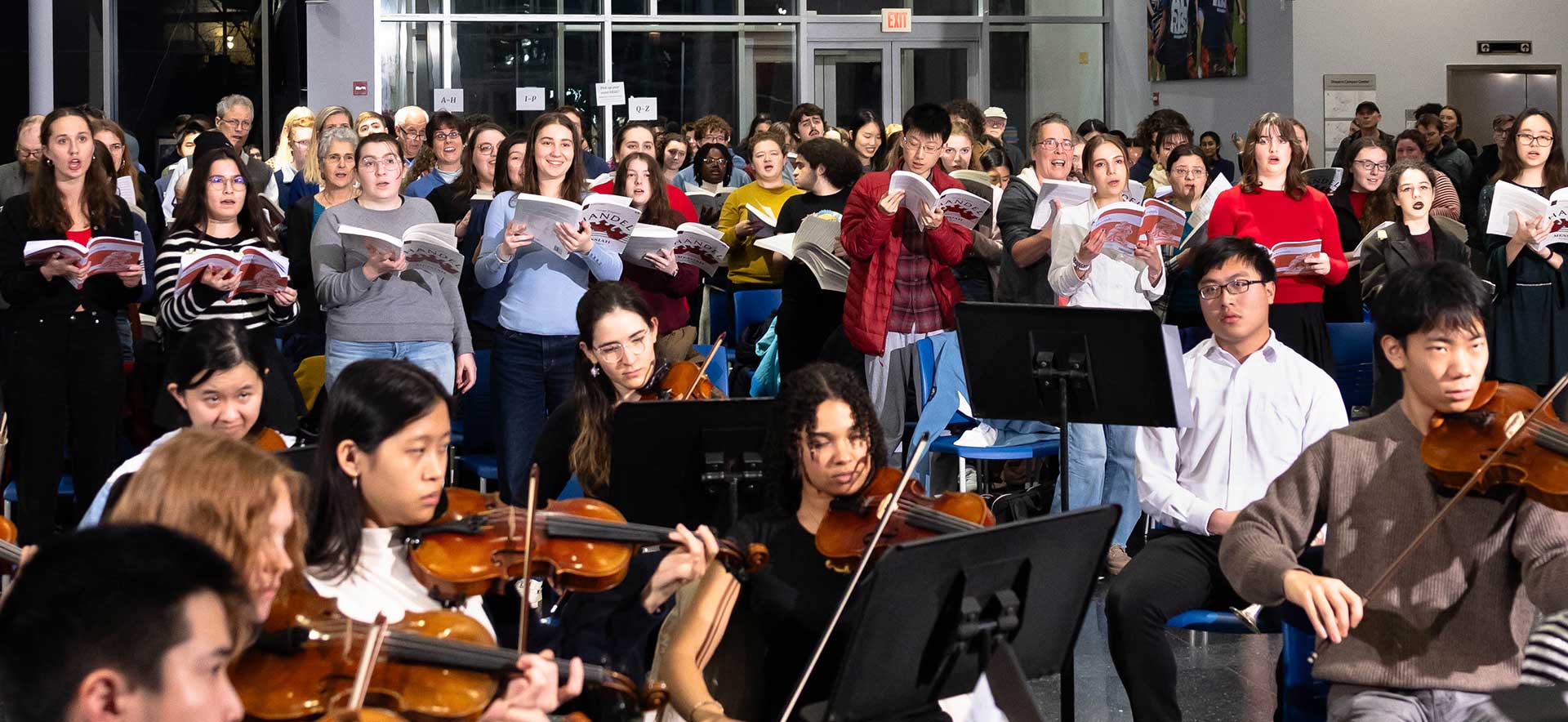 The Brandeis-Wellesley Orchestra and University Chorus performing and community members singing at the annual holiday concert.
