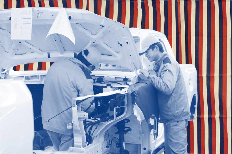 Red, white and blue striped background. Two people working under the hood of a truck.